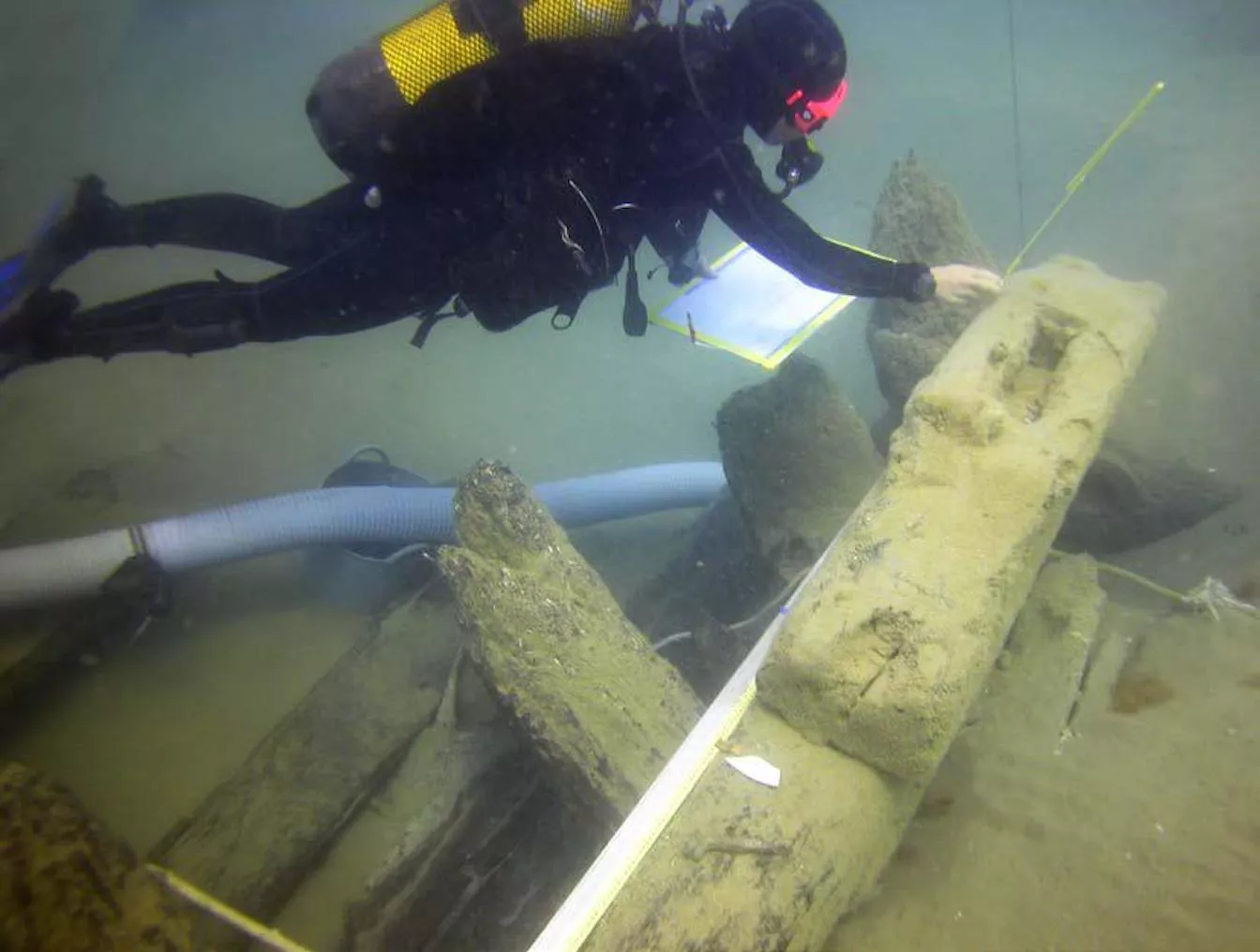 Un arqueòleg examina la peça de fusta sostenia el pal situat més a popa