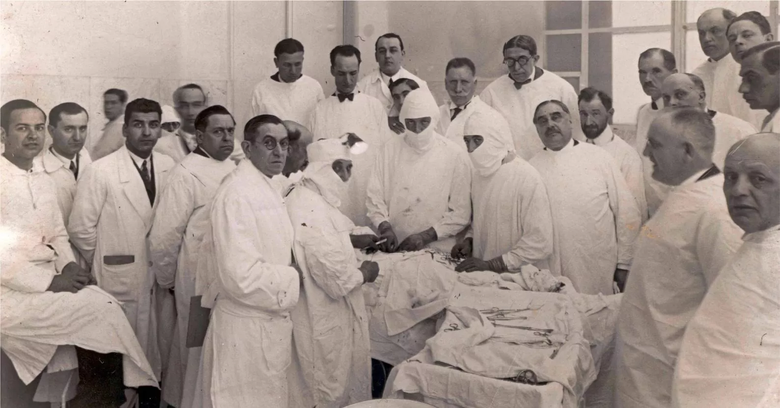 Els doctors Josep Trueta i Manuel Corachan practiquen un procediment quirúrgic davant la mirada d’altres col·legues en una fotografia de la dècada del 1930