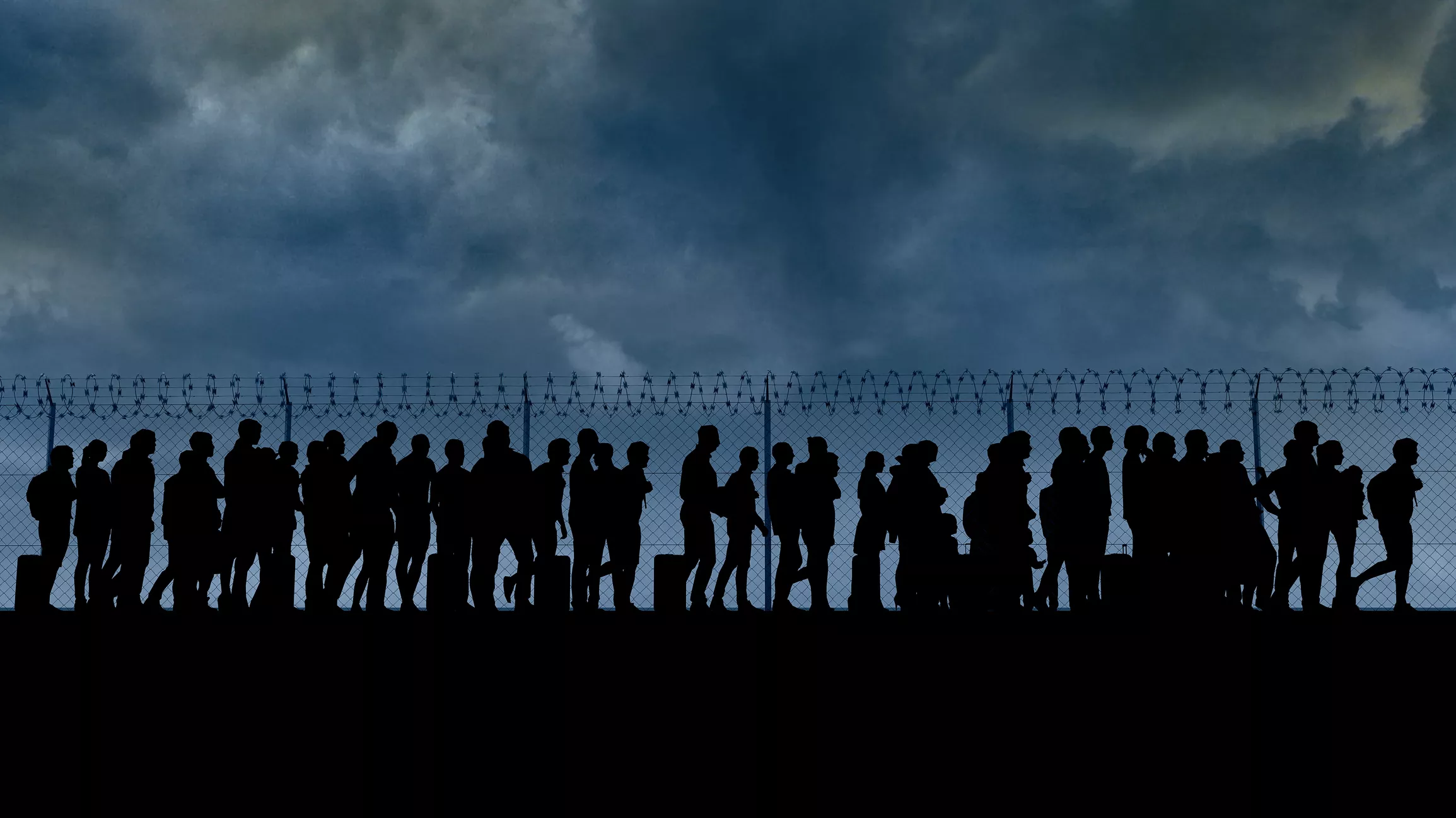 Refugiats sirians caminen davant la valla d'espines