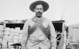 Pancho Villa vestit amb bandoleres davant dun campament d'insurrectes
