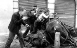La fotografia original ‘Guàrdies d’assalt al carrer Diputació’ mostra quatre homes, tres d'ells recolzats sobre uns cavalls morts
