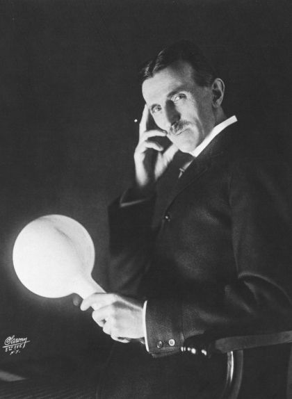 Nikola Tesla sostenint una làmpada en un dels seus experiments